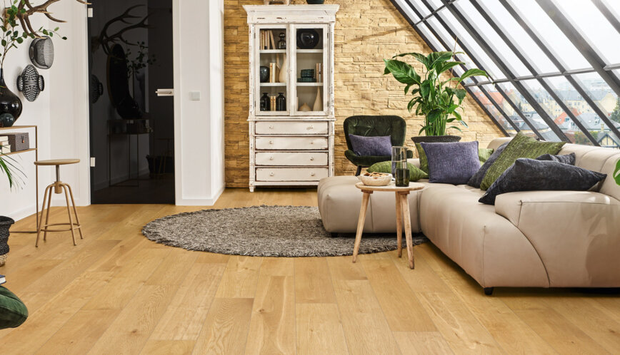 Modernes Wohnzimmer mit großen Dachfenstern, Eichenparkett, beiger Ledercouch und grünen Pflanzen; gemütliche Einrichtung mit Vintage-Vitrine.